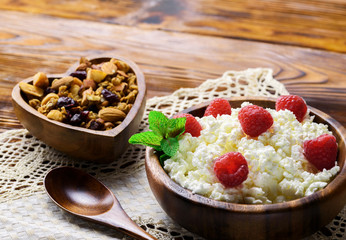 Cottage cheese with fresh raspberry in a wooden bowl on old wooden background with copy space for your text. Top view