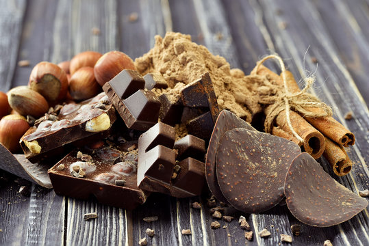 Chocolate pieces with nuts on dark wooden background. Selective focus. Rustic style.