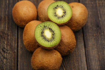 Kiwi fresh whole and halves on a black wooden table. Kiwi fruit is useful.