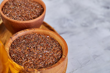 Flax seeds in bowl and flaxseed oil in glass bottle on light textured background, top view, close-up, selective focus