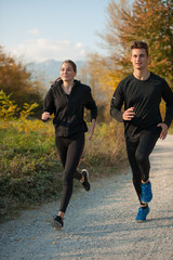 Obraz premium Young veautiful couple runs on a path in park on autumn afternoon