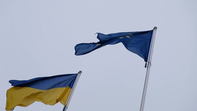 Flag of Ukraine and flag of European Union fluttering on a background of a rainy sky
