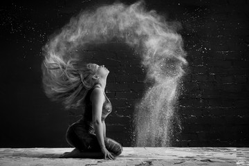 girl in a cloud of dust outlines an arc wave of hair. black and white photo