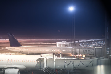 Fototapeta premium Parked aircrafts on an international airport through the gate windows