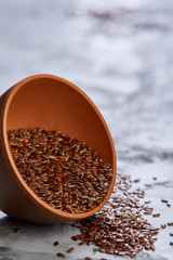 Flax seeds in bowl and flaxseed oil in glass bottle on light textured background, top view, close-up, selective focus