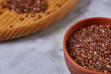 Flax seeds in bowl and flaxseed oil in glass bottle on light textured background, top view, close-up, selective focus