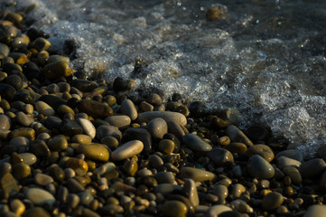 pebble stones on the sea beach, the rolling waves of the sea with foam
