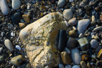 pebble stones on the sea beach, the rolling waves of the sea with foam