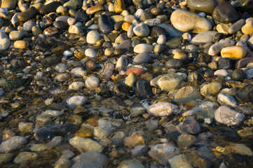pebble stones on the sea beach, the rolling waves of the sea with foam