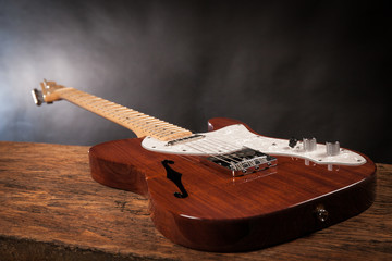 Vintage electric guitar on a wood raw table. Musical instrument. Black background with smoke