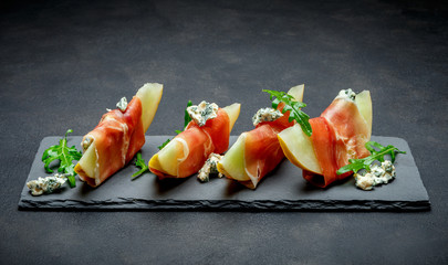 italian food with melon and prosciutto on stone board
