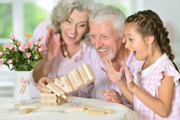 grandparents and granddaughter playing with wooden blocks