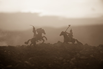 Fototapeta na wymiar Joust between two knights on horseback. Sunset on background. Selective focus