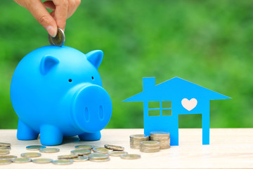Finance,Blue house model and tack of coins money with blue piggy on natural green background, Investment business and Banking concept