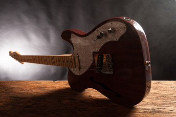 Vintage electric guitar on a wood raw table. Musical instrument. Black background with smoke