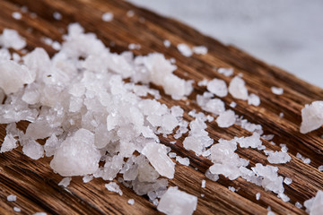 Pile of salt crystals on the dark wooden background, top view, flat lay, shallow depth of field