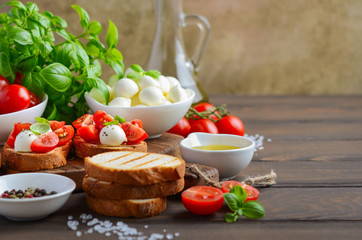 Bruschetta with cherry tomatoes and mozzarella on rustic wooden background, selective focus.