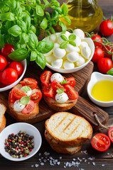 Bruschetta with cherry tomatoes and mozzarella on rustic wooden background, selective focus.