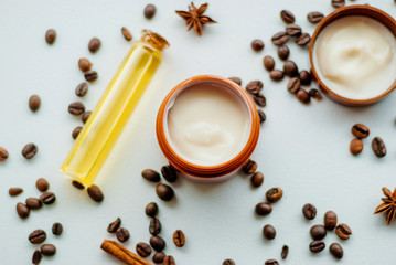 Jar of caffeine cream and coffee beans on white background, top view