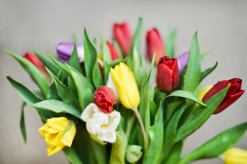 Obraz premium Flower background: bouquet of colorful tulips in a glass vase on a natural wooden background, postcard, mocap for mother's day greetings, international women's day