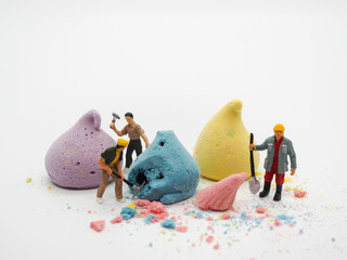 Miniature worker and colorful merengue on white background, selective focus. sweet dessert