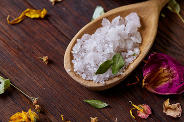 SPA concept: composition of spa treatment with natural sea salt, aromatic oil and flowers on wooden background