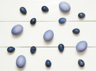 Colorful quail eggs on white wooden background.
