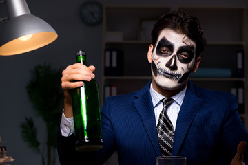 Businessman with scary face mask working late in office