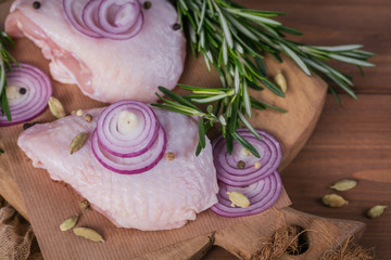 Obraz na płótnie Canvas Raw chicken thighs with rosemary, red onion and peppercorns