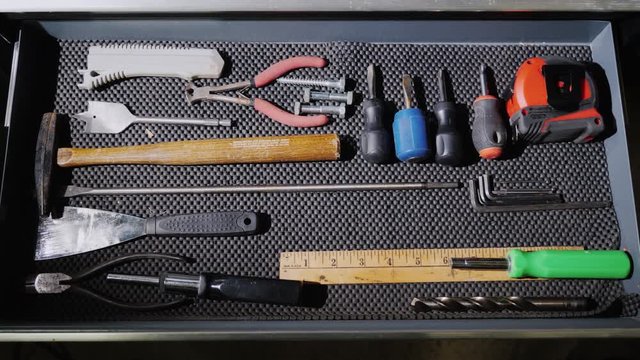 A man opens a box with hand tools and takes one of them