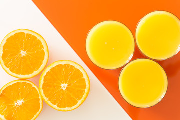 Orange juice and fruits on the white-orange glass background.