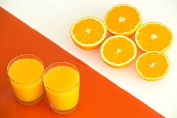 Orange juice and fruits on the white-orange glass background.