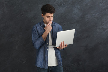 Young serious man using laptop computer