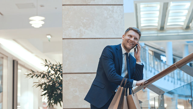 Young businessman with shopping bag talking on the phone