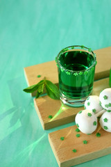 Green alcoholic drink and cake pops on green background