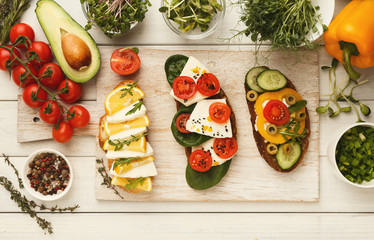Assortment of bruschettas on wooden kitchen table, top view