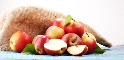 Ripe red apples with leaves on blue background.