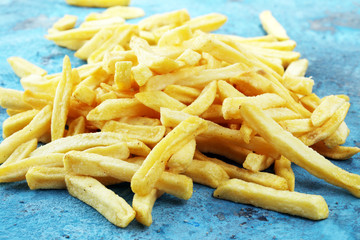 Tasty french fries on blue table background