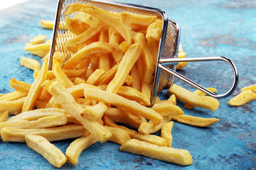 Tasty french fries on blue table background