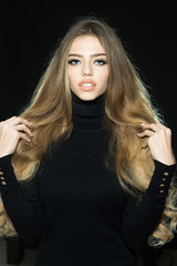 Fototapeta premium Gorgeous long hair. Sensual blonde model in black clothes. Beautiful girl face makeup. Fashion woman hair style. Passionate sexy attractive beautiful blonde girl with healthy long hair, perfect makeup
