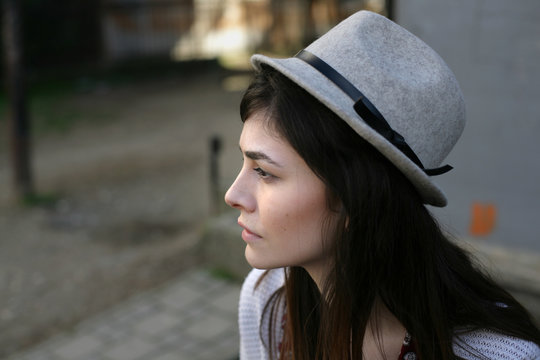 Portrait of a young woman with hat; profile view.