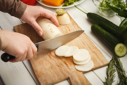 Woman cutting fresh turnip on wooden board