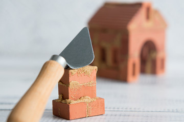 trowel with bricks on the background of a toy house