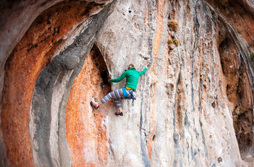 A woman climbs the rock.