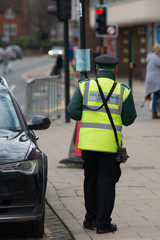 civil enforcement officer traffic warden issuing ticket to car parked incorrectly with fixed...