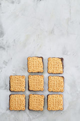 Square biscuits arranged in pattern on light textured background, close-up, shallow depth of field, selective focus.