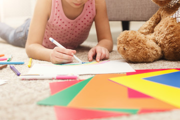 Smiling little girl drawing with colored pencils at home