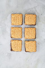 Square biscuits arranged in pattern on light textured background, close-up, shallow depth of field, selective focus.