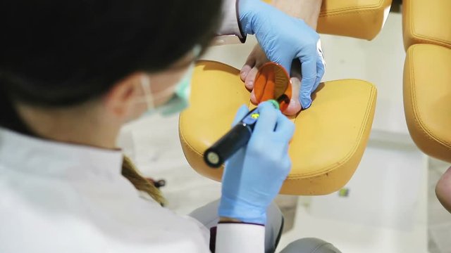 hands of a doctor of Podiatry is heated by the device the nail of male patient in the beauty salon, close-up