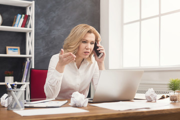 Serious business woman at work talking on phone
